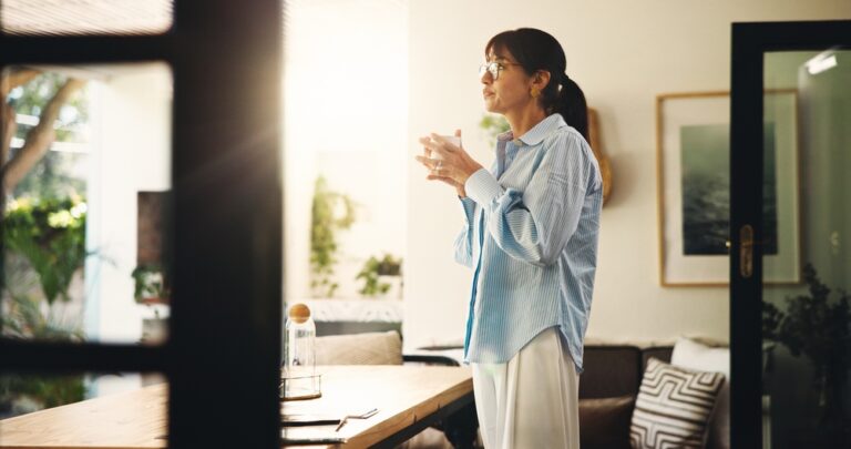 Midlife woman with coffee reflecting calmly at home — deciding about hormone replacement therapy
