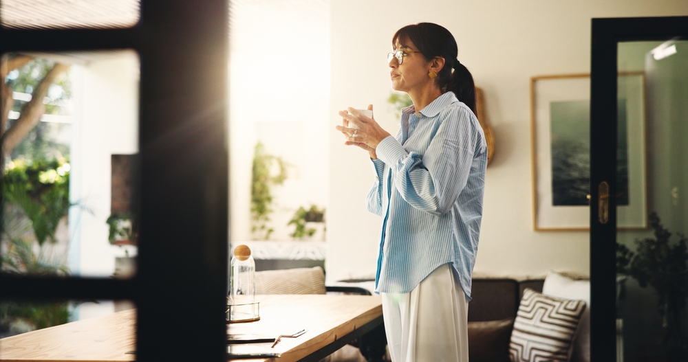Midlife woman with coffee reflecting calmly at home — deciding about hormone replacement therapy