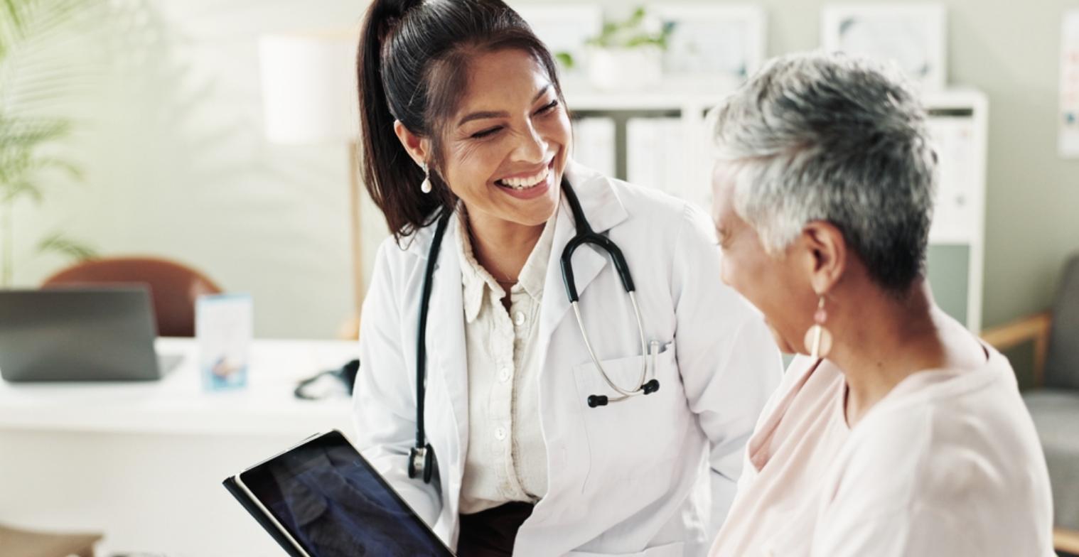 A physician reviews results on a tablet with a smiling midlife patient during an unhurried concierge visit
