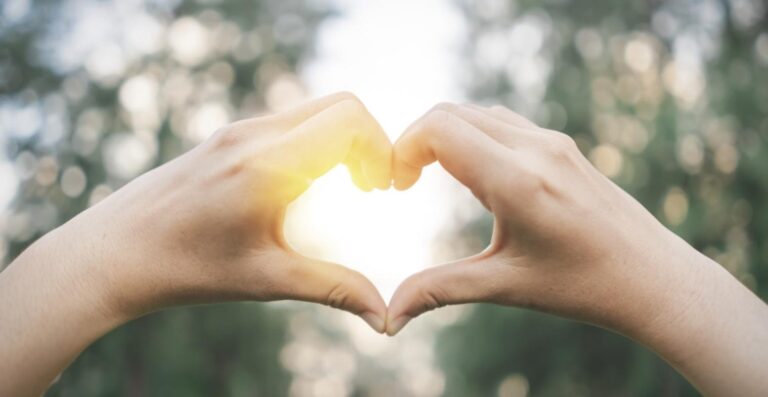 Hands forming a heart shape against soft morning light, a symbol of prevention and early detection
