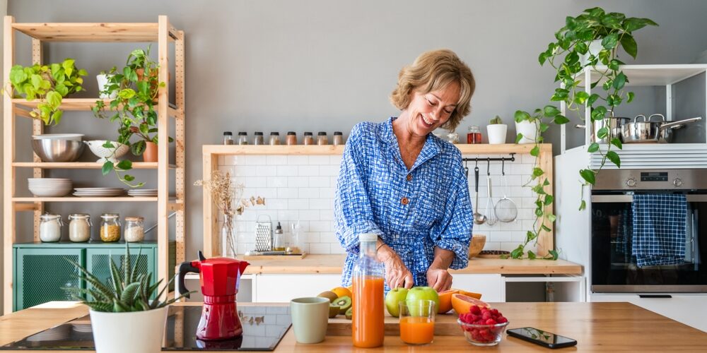 Midlife woman preparing a healthy meal with fresh fruit in her kitchen