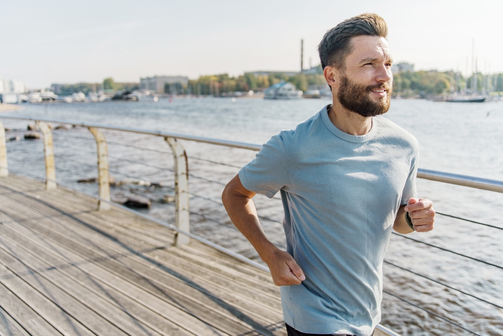 Man jogging along a waterfront in morning light