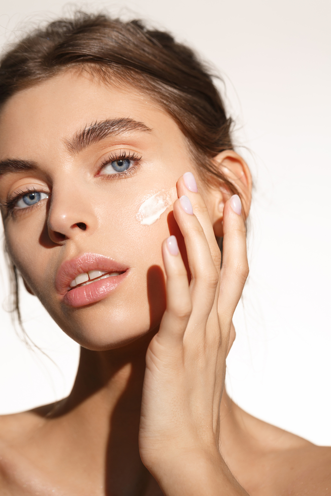 Woman applying a small amount of face cream to her cheek